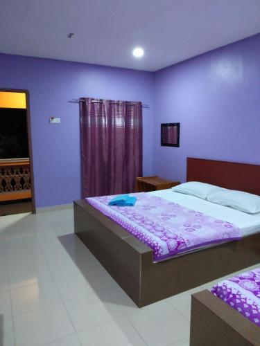 a bedroom with a bed and a purple wall at Inapan Aishah in Pantai Cenang