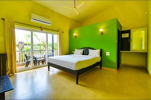 戈阿韦尔哈FabEscape Vagator Retreat Resort With Swimming Pool - Nr Vagator Beach的一间卧室，配有一张床和绿色墙壁