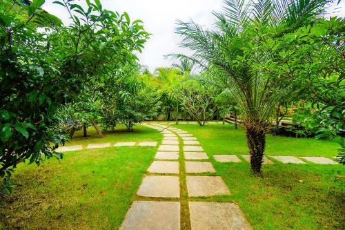 a pathway in a park with a palm tree at FabEscape Vagator Retreat Resort With Swimming Pool in Goa Velha