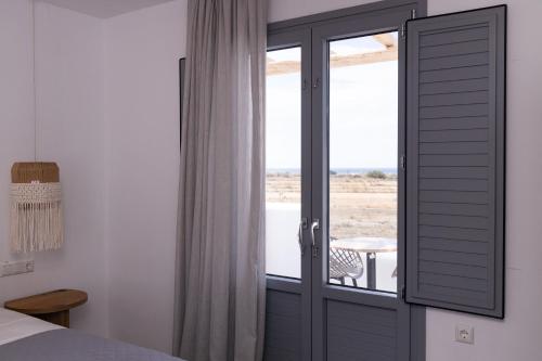 a bedroom with a door with a view of the ocean at verykokkos collection suites mikri vigla in Mikri Vigla