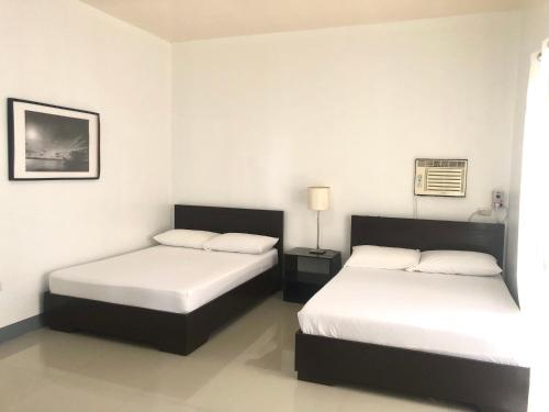 two beds in a room with white walls at Paguia’s Cottages in Mambajao