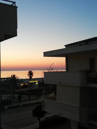 um pôr-do-sol sobre o oceano e um edifício com um edifício em Marconi House em Alba Adriatica