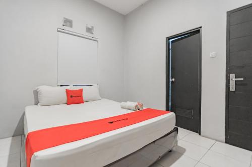 a bedroom with a bed with a red blanket on it at RedDoorz near Exit Toll Pasteur 4 in Bandung