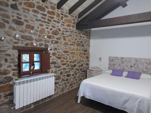 a bedroom with a bed and a stone wall at Apartamentos la casa de los ríos in Liérganes