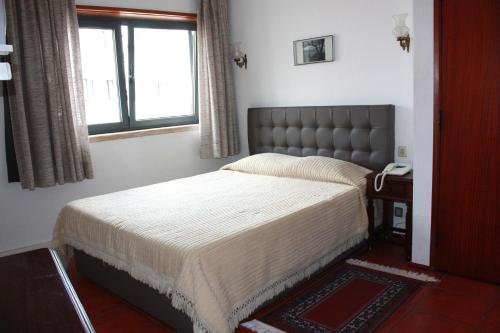 a bedroom with a bed and a window and a phone at Hotel Dona Leonor in Caldas da Rainha