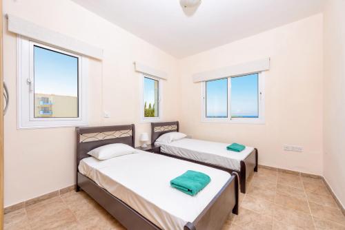 2 Betten in einem Zimmer mit 2 Fenstern in der Unterkunft Villa Irina in Paralimni