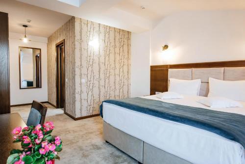 a hotel room with a bed and a table and flowers at Hotel Buchenland in Gura Humorului