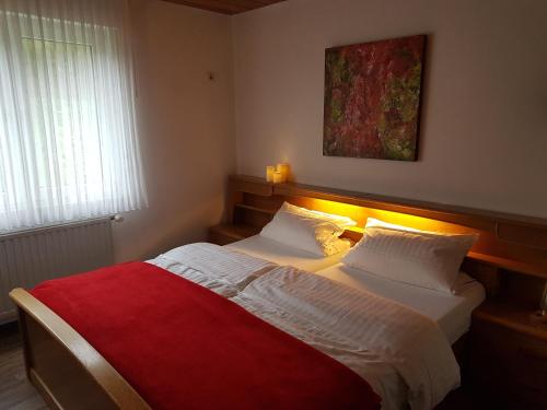 a bedroom with a large bed with a red blanket at Gasthof-Pension Hunaustuben in Schmallenberg