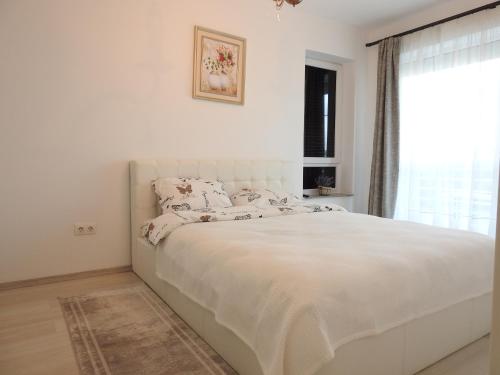 a white bed in a bedroom with a window at TRUST Apartaments 2 in Braşov