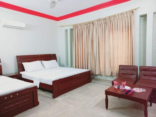 a bedroom with two beds and a couch and a table at Cosy Inn Guest House Karachi in Karachi