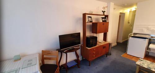 a living room with a tv and a dresser with a tvicterictericter at Garden Room in Plymouth
