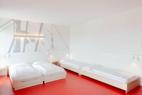 two beds in a room with a red floor at havenhostel Cuxhaven in Cuxhaven