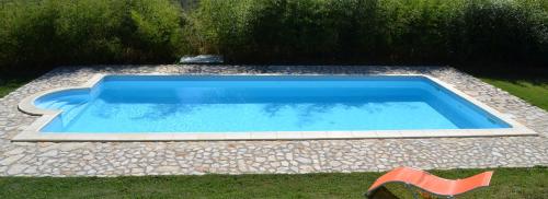 uma piscina azul com uma cadeira na relva em B&B al Pozzolone em Montieri