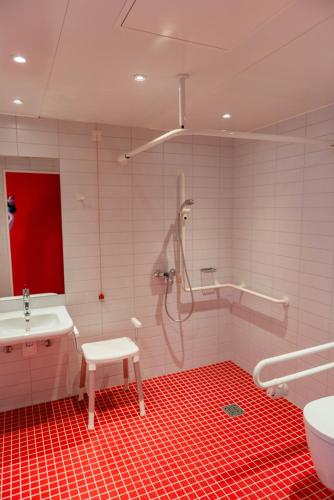 a bathroom with a shower and a red floor at havenhostel Cuxhaven in Cuxhaven