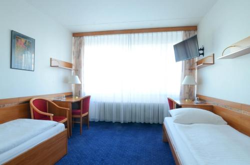 プラハにあるHotel ILFのベッド2台、デスク、窓が備わる客室です。