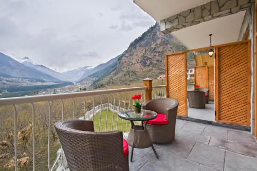 a balcony with a table and chairs and mountains at The Whitestone Resorts in Manāli