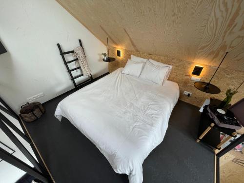 1 dormitorio con 1 cama grande con sábanas blancas en Le Studio du Designer en Libin