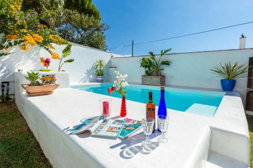 a table with wine bottles and glasses next to a pool at La Ballena Azul CONIL in Cádiz