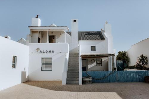 a white house with a blue fence in front of it at Aloha 1 in Paternoster
