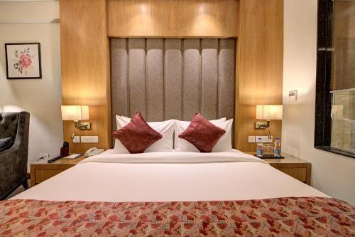 a hotel room with a large bed with red pillows at Best Western Plus Revanta Mcleod Ganj in Dharamshala