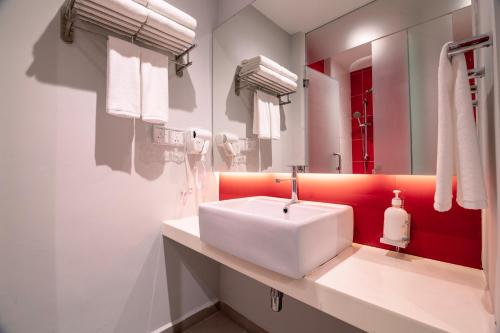 a bathroom with a white sink and a red wall at Holiday Inn Express & Suites Johor Bahru by IHG in Johor Bahru
