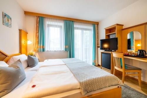 a hotel room with a large bed and a desk at Sportpension Bergblick in Wagrain