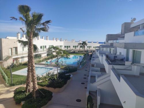 widok na budynek z basenem i palmami w obiekcie Apartamento La Invencible Mojacar 1ª Línea Playa w mieście Mojácar