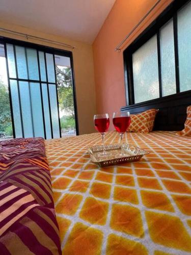 two glasses of red wine sitting on top of a bed at Suman Madhu Mansion in Nānodra