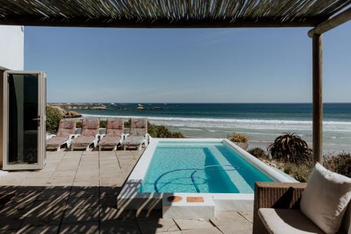 a swimming pool with chairs and the ocean in the background at As it is in Heaven in Paternoster