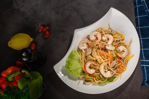 a plate of noodles with shrimp and vegetables on a table at Holiday Inn Express & Suites Johor Bahru by IHG in Johor Bahru