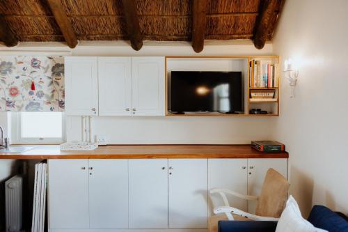 a kitchen with white cabinets and a flat screen tv at As it is in Heaven in Paternoster