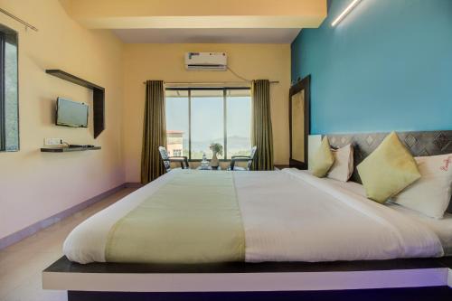 a bedroom with a large bed with a large window at Evergreen Holidays Mahabaleshwar in Mahabaleshwar