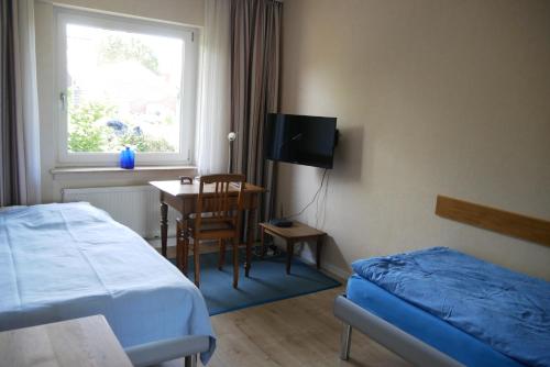 a bedroom with a bed and a table and a window at Ferienwohnung Illerhues in Ascheberg