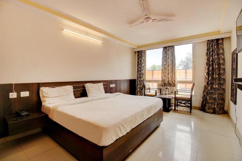 a bedroom with a bed and a table and a window at FabHotel PS Grand in Lucknow