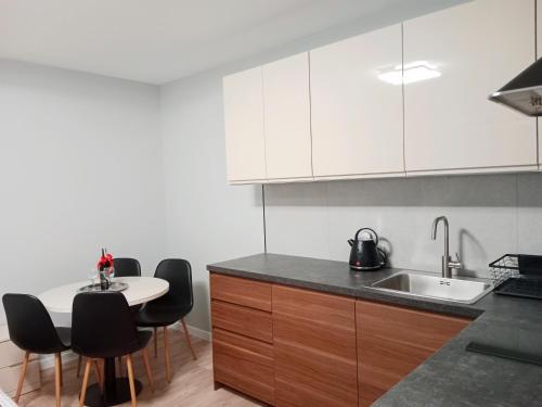 a kitchen with white cabinets and a table and chairs at Apartamenty Radom Klwatecka 20 in Radom