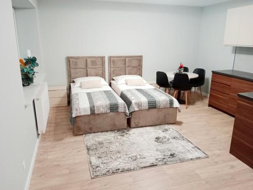 a bedroom with two beds and a table with chairs at Apartamenty Radom Klwatecka 20 in Radom