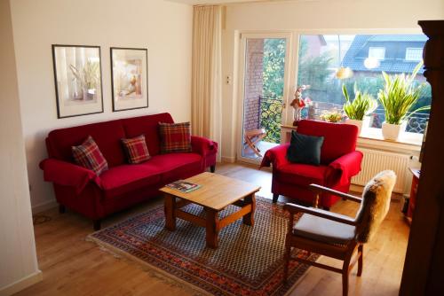 a living room with two red couches and a table at Ferienwohnung Illerhues in Ascheberg
