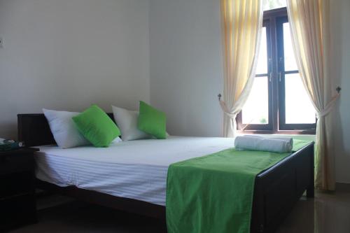 Un dormitorio con una cama con almohadas verdes y una ventana en Queens Airport Residence en Negombo