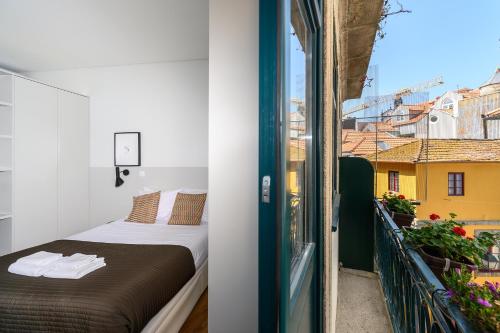 a bedroom with a bed and a balcony with a view at Maria da Sé Historic House in Porto