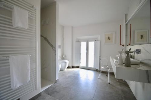 a white bathroom with a sink and a toilet at Rubiera Relais B&B in Rubiera