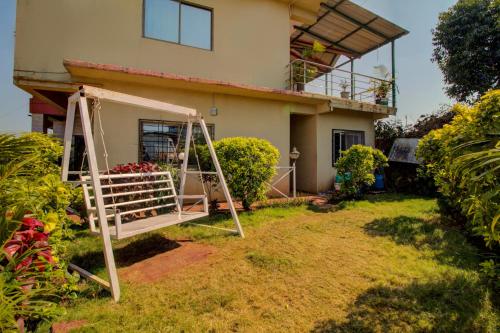 a house with a swing in front of it at Evergreen Holidays Mahabaleshwar in Mahabaleshwar