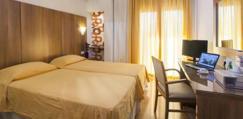 a hotel room with a bed and a desk with a laptop at Leto Boutique Hotel Agrinio in Agrinion