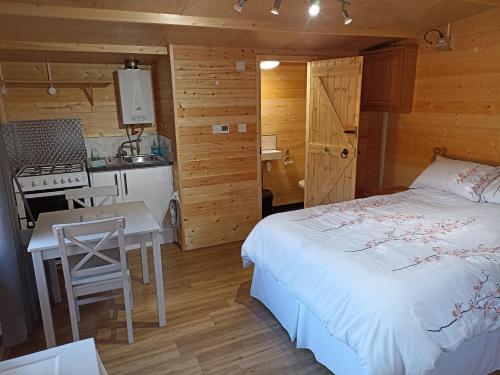 um quarto com uma cama, uma mesa e uma cozinha em Cosy Cabin em Stock