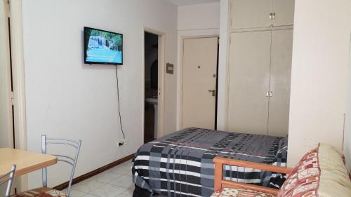 Habitación pequeña con cama y TV en la pared. en Falucho en Mar del Plata