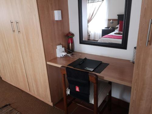 a room with a desk with a mirror and a bed at De Oude Herberg in Centurion