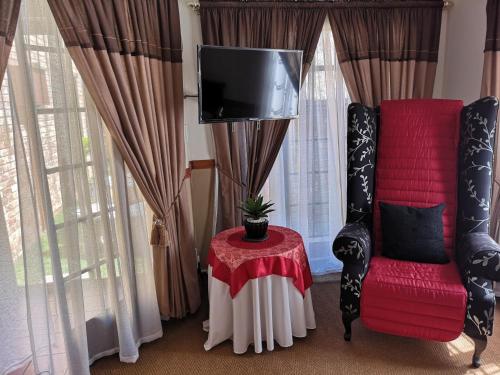 a living room with a red chair and a tv at De Oude Herberg in Centurion