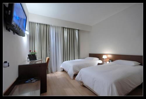 a hotel room with two beds and a flat screen tv at Pharae Palace in Kalamata