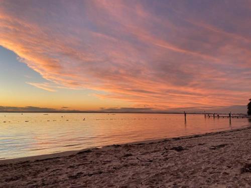 a sunset on the beach with birds in the water at Nuts About the Bay in Nelson Bay