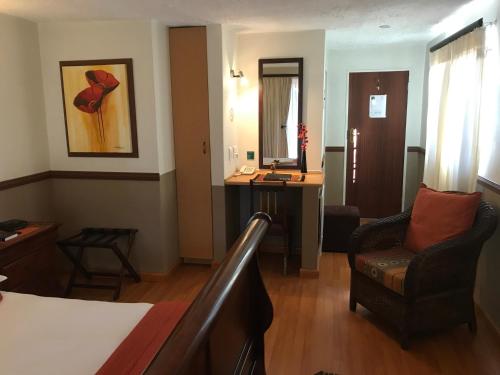 a hotel room with a bed and a chair and a mirror at De Oude Herberg in Centurion