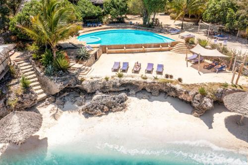an aerial view of a pool with chairs and a beach at Marafiki Bungalows in Kiwengwa